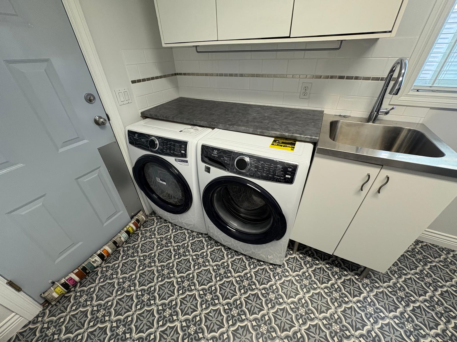 Completed laundry room renovation by Knock and Known — tile flooring, countertop, and appliance install